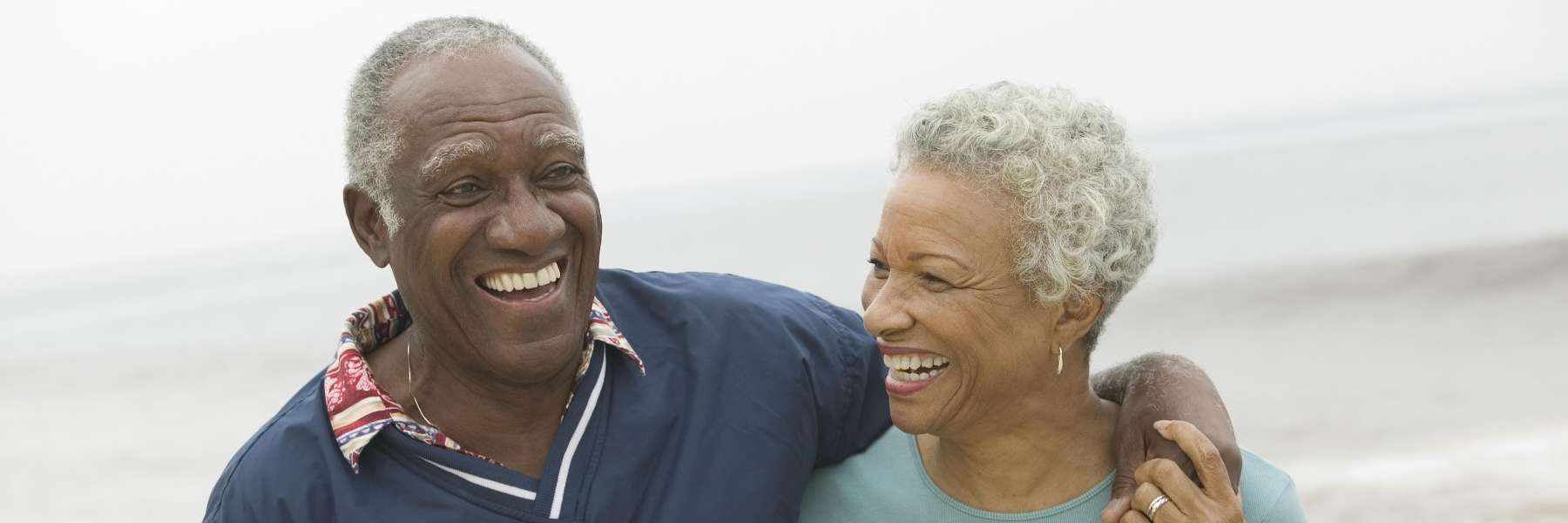 middle-aged man and woman smiling while walking on the beach